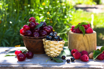 Fresh cherry, currant, raspberry  in bowl / Top view red ripe cherry fruit and green leaf on natural background