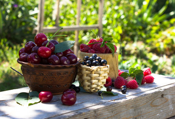 Fresh cherry, currant, raspberry  in bowl / Top view red ripe cherry fruit and green leaf on...
