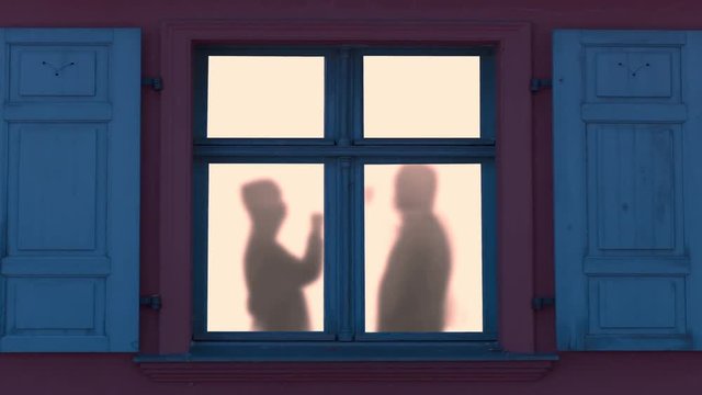 Menschliche Schatten hinterm Fenster prosten sich zu und feiern fr&ouml;hlich
