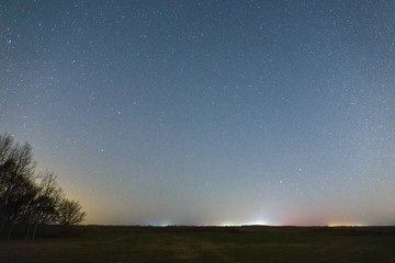 Fototapeta na wymiar Green field late at night. Starry sky with thousands of stars