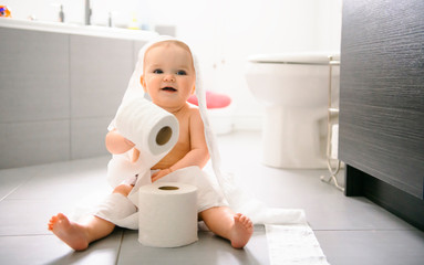 Toddler ripping up toilet paper in bathroom