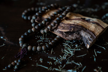 Buddhist sacred mala meditation beads on wooden table with a piece of Palo Santo wood and...