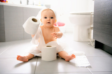 Toddler ripping up toilet paper in bathroom