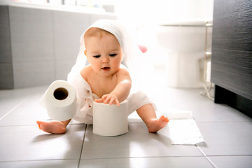 Toddler ripping up toilet paper in bathroom