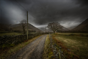 Gravel road with fog against mountains. Lake District National Park