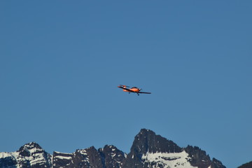 Fototapeta na wymiar un avión naranja volando sobre las montañas