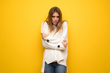 Fototapeta premium Blonde woman over yellow wall freezing