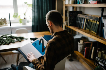 A man sits at the table and writes on a notebook.