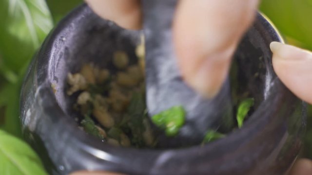 A vintage pestle while a woman is working to prepare italian pesto