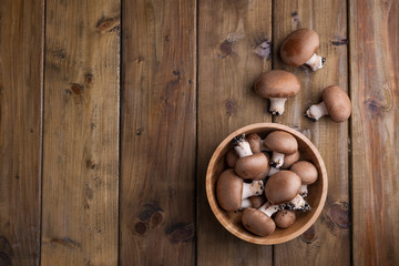 Champignon mushrooms, sacking mat and spices on wooden background. Wooden dishes. Photo in a rustic style. Place for text,