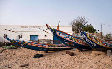 Fototapeta na wymiar Mbour, Senegal: Colourful fishing boats stranded in the sand