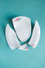 broken white plate on blue background, copy space, top view