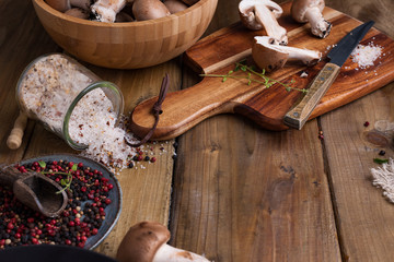 Champignon mushrooms with red onions and spices on a wooden background, wooden utensils. Rustic style photo. Vegetarian lunch of vegetables. Place for text,