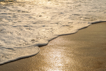 Close up shot of waves breaking on the sandy beach at sunrise