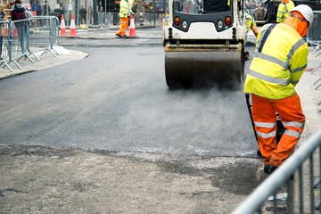 Men at work asphalting street pavement in London, UK, march 2019.