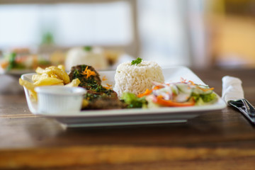 grilled beef steak served on plate withh rice, salad and frites. Selective focus photography