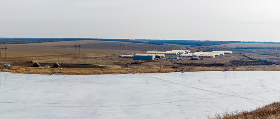 The panoramic view of buildings of the agricultural farm on the coast of the frozen river. Rostov-on-Don region, Russia