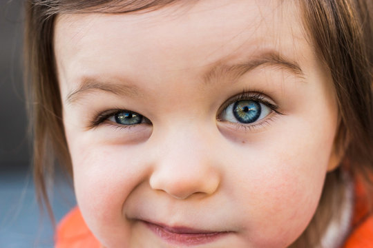 Funny Child Toddler Girl Winking Her Eye. Closeup Portrait, Beautiful Blue Baby Eyes