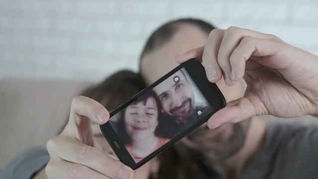 Selfie on smartphone. Funny little girl with dad are photographed on a smartphone.