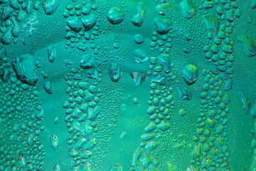 Random water drops on glass surface with green light background