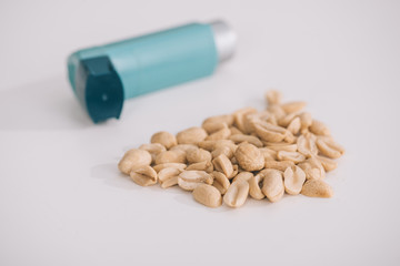 selective focus of tasty nutritious peanuts near blue inhaler on grey