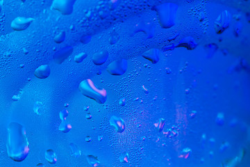 Random water drops on glass surface with blue light background