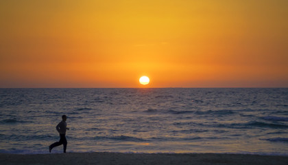 man running by the sea at sunset