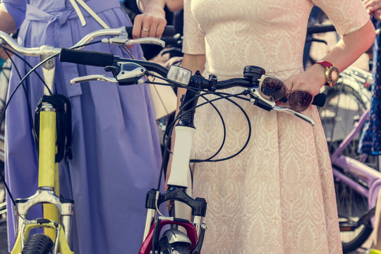 Concept: women on bicycles.  Woman in bright clothes hold the handlebars. Part of the picture.