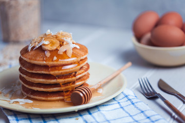 stack of pancakes with honey and banans
