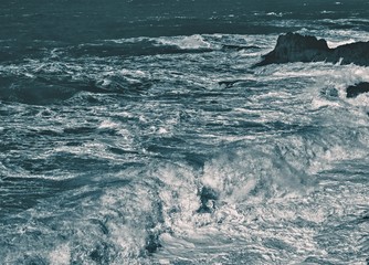 Stormy waves with splashes and foam on the ocean surface during a storm