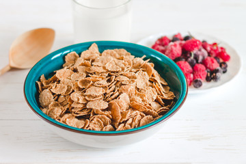 Breakfast cereal with milk on a white background. Flakes on a plate. Muesli with berries and milk