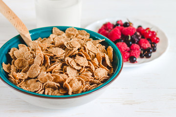 Breakfast cereal with milk on a white background. Flakes on a plate. Muesli with berries and milk