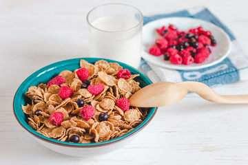 Breakfast cereal with milk on a white background. Flakes on a plate. Muesli with berries and milk