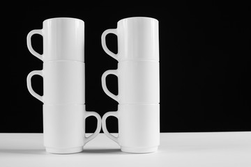 Arrangement of six white mugs with a handle. Black background