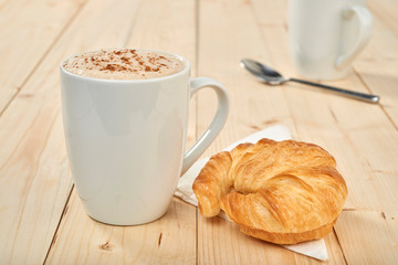 Coffee and croissants on wooden table