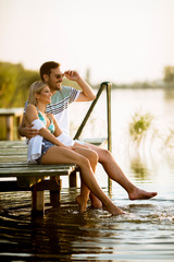 Loving couple sitting on the pier on lake
