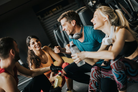 Friends in sportswear talking and laughing together while resting in the gym after a workout