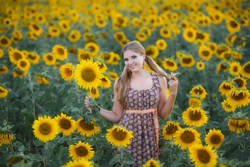Fototapeta na wymiar Young beautiful girl in a field of sunflowers
