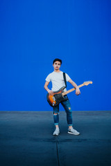 Fototapeta na wymiar young man with electric guitar on blue background