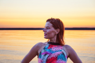 Portrait of a red-haired wet middle-aged woman in a swimsuit on a summer evening after sunset.. Close-up.
