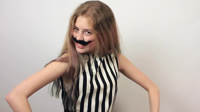 Funny beautiful girl with hat and fake moustache having fun. Positive girl on grey background.
