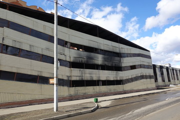 Multi-storey parking after a fire. Copy-darkened windows with burned out cars inside