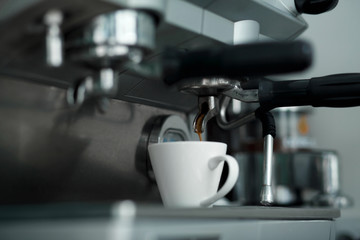 Fototapeta na wymiar Coffee machinne pours freshly brewed coffee in white cup