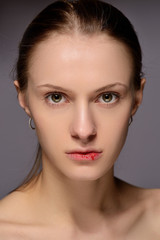 portrait of a young beautiful girl with blood on her lips, on a gray background.