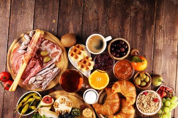 breakfast on table with bread buns, croissants, coffe and eggs