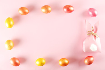 Golden and rose gold Easter eggs in beautiful flat lay pastel colored composition on pale pink paper background. Top view, copy space.