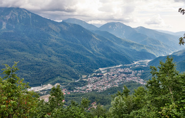 Naklejka na ściany i meble Village in a mountain valley among the green forest.