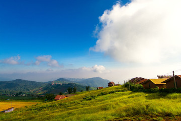 The village on the hill and the grass fields, the backdrop of the mountains and the beautiful sky.