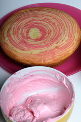 Baked biscuit cake. For cooking cake with layers of different colors. Next to the containers of cream of pink colors.