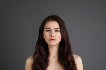 Fototapeta premium Close up portrait of offended unhappy beautiful woman with long brunette hair, bare shoulders